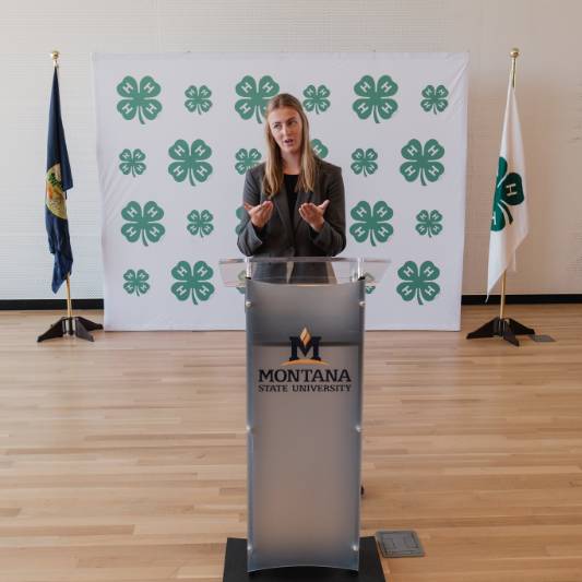teen member standing in front of montana state University podium speaking