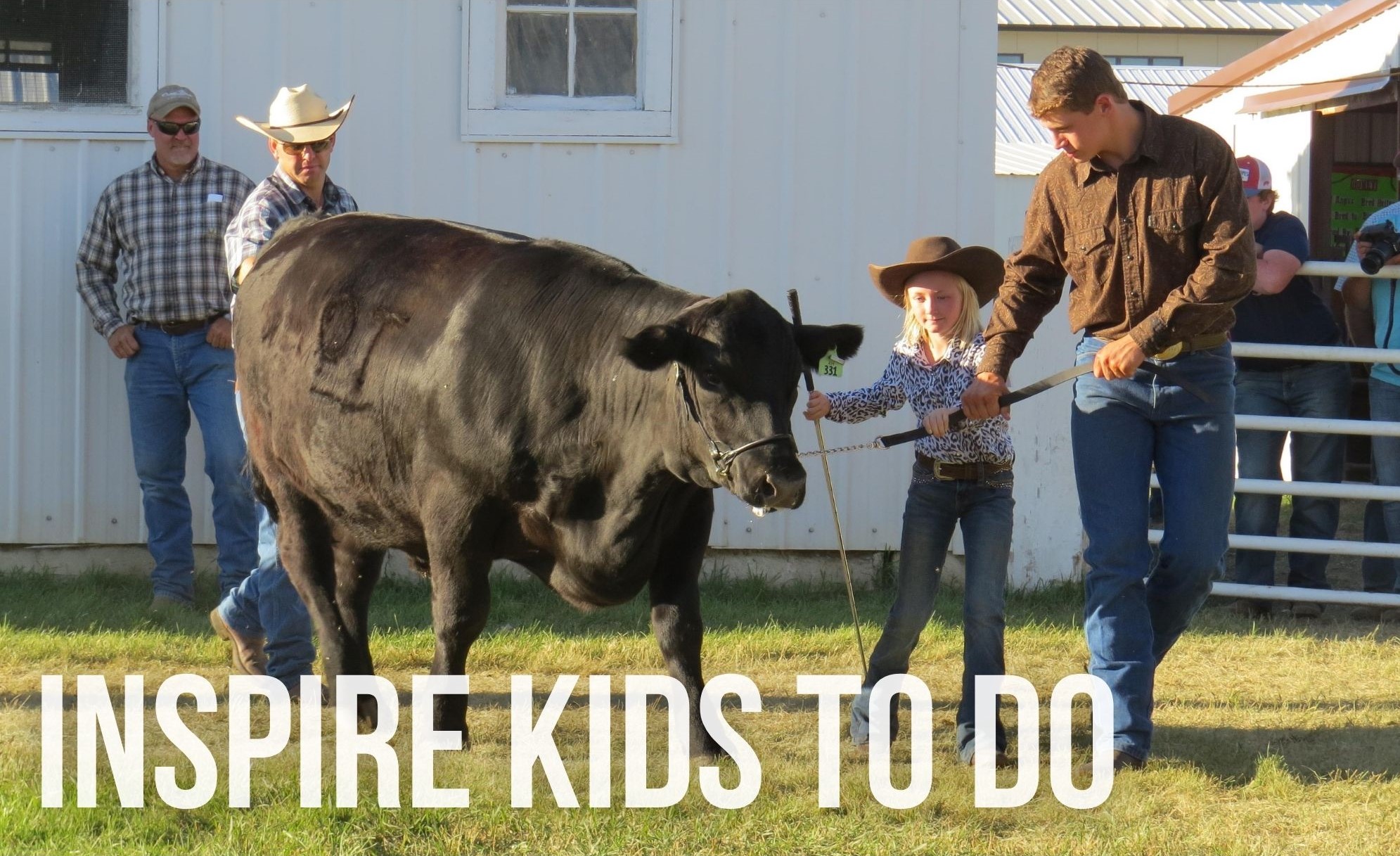 A male volunteer helps a female club member with her steer. Text: Inspire to do